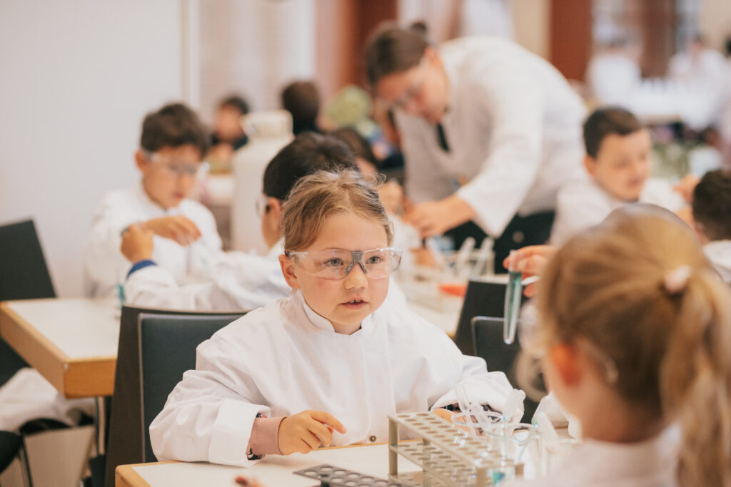 Kinder experimentieren in weißen Kitteln