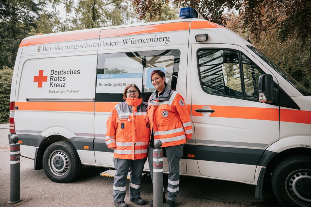 Zwei Rettungskräfte stehen vor dem Rettungswagen