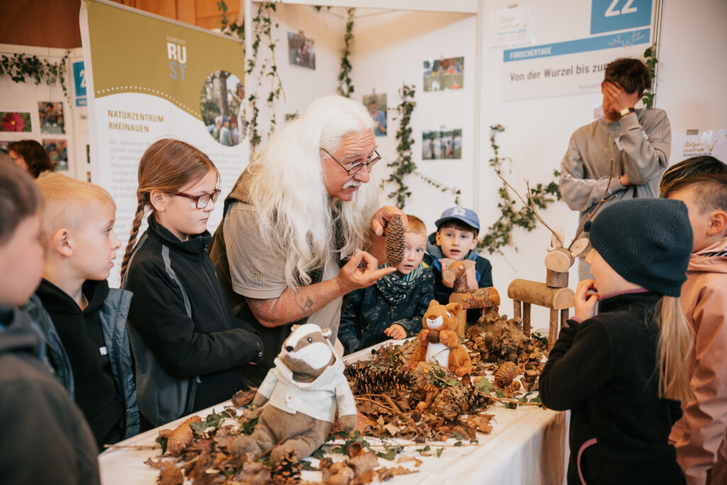 Mann erklärt Kindern etwas über Bäume